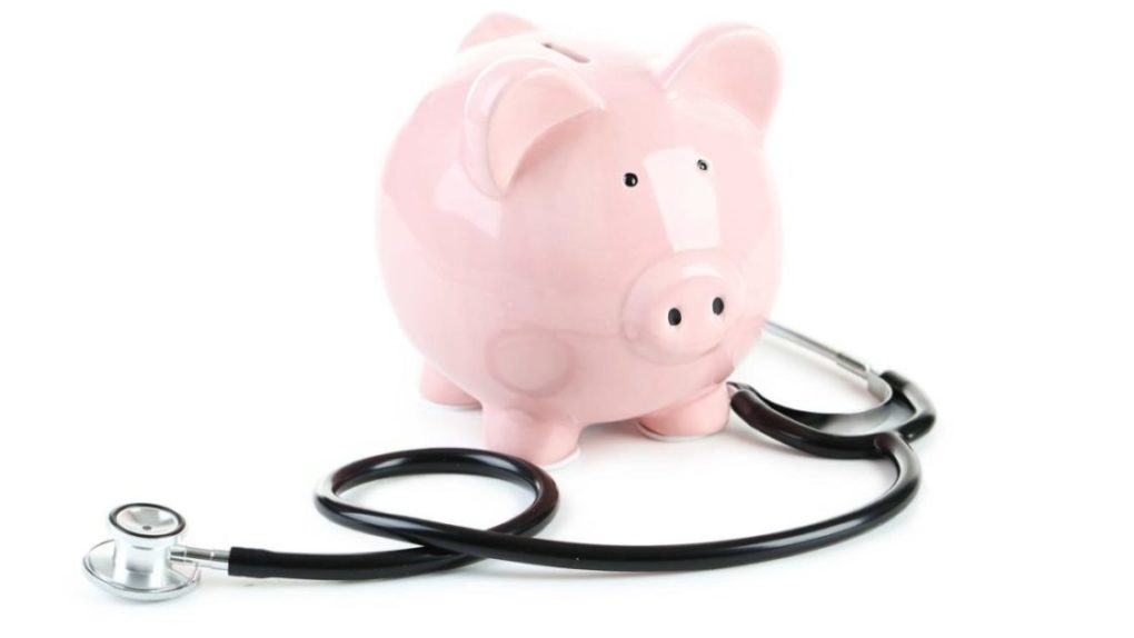 Pink piggy bank with stethoscope isolated on a white